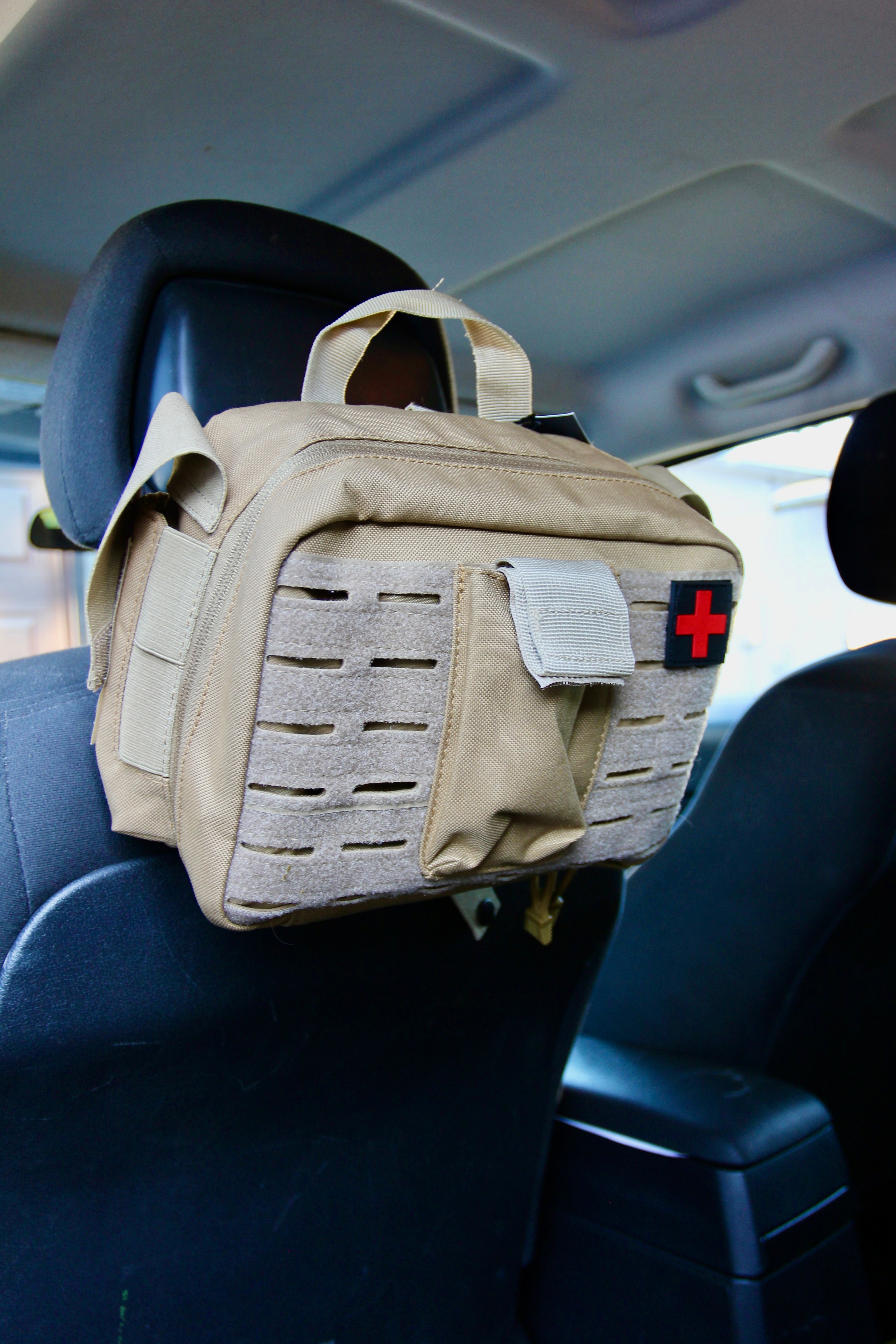 Tan Police2Bag Bag Only mounted securely to a vehicle headrest using its attachment strap system.